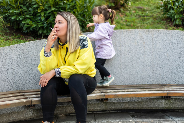 a woman smoking a joint next to a toddler
